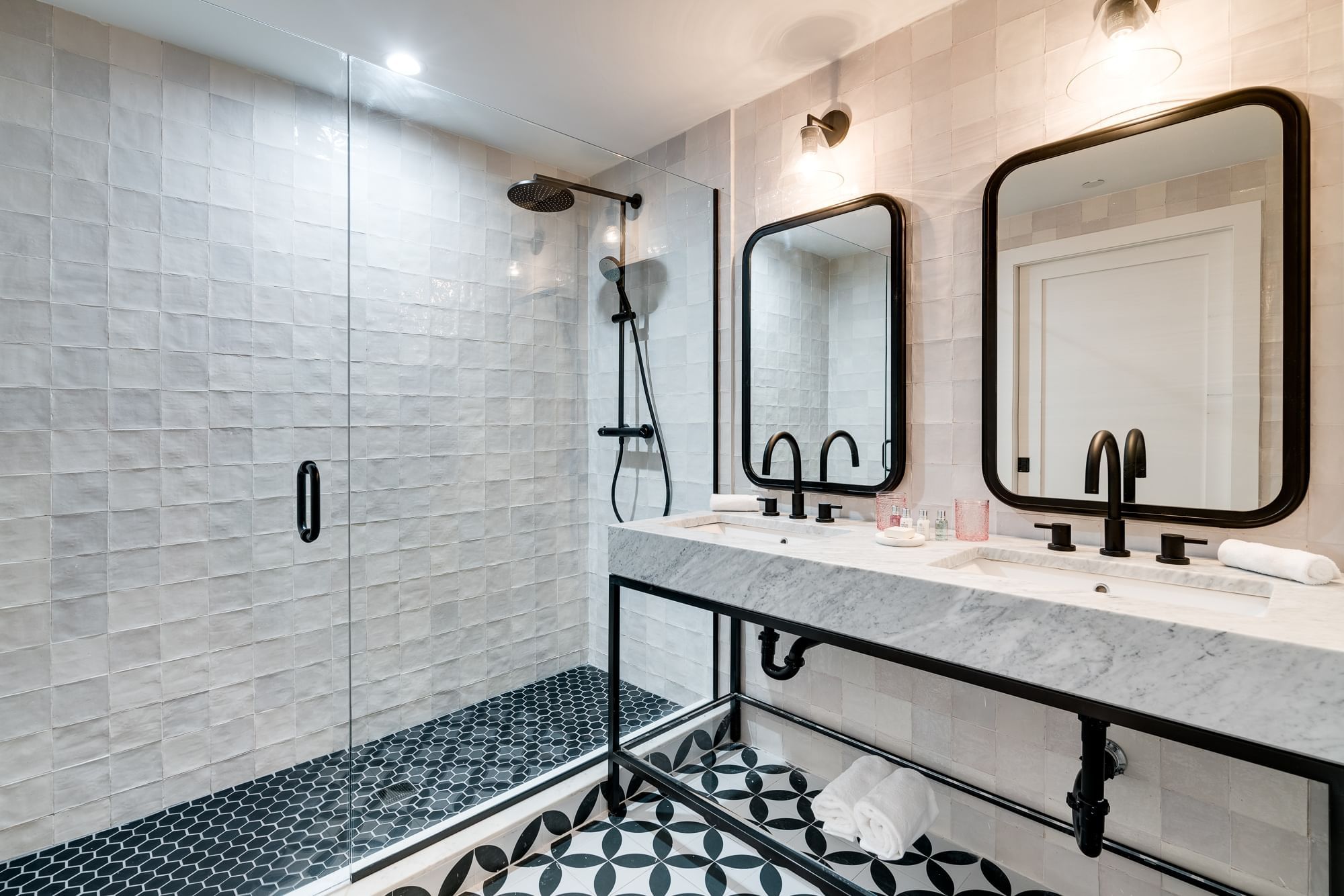 A modern bathroom with a large walk-in shower, a double vanity with two sinks, and a tiled floor.