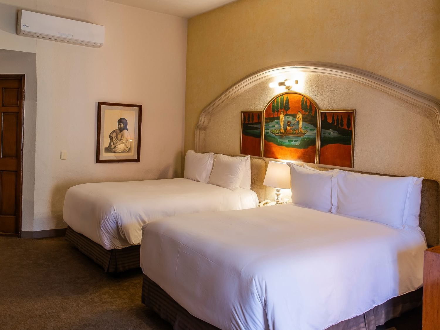 Spacious room with two double beds, arched alcove, artwork, and warm lighting at Quinta Real Zacatecas