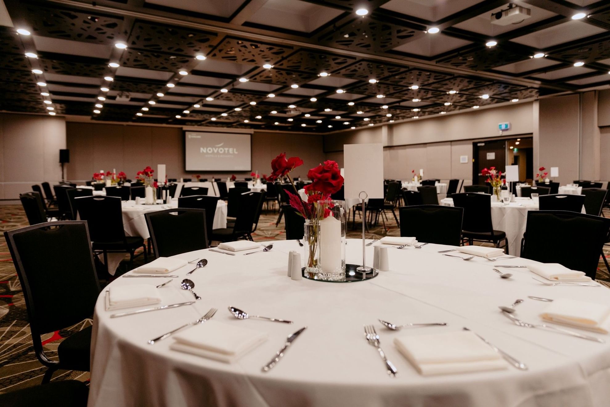 A large banquet hall with set tables and chairs at Novotel Sydney Parramatta