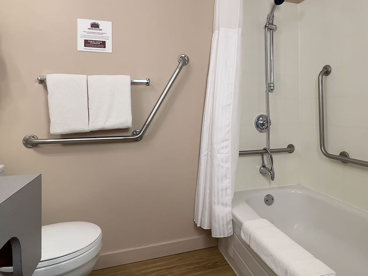 Accessible bathroom with sink, bathtub, grab bar, toilet, and towels