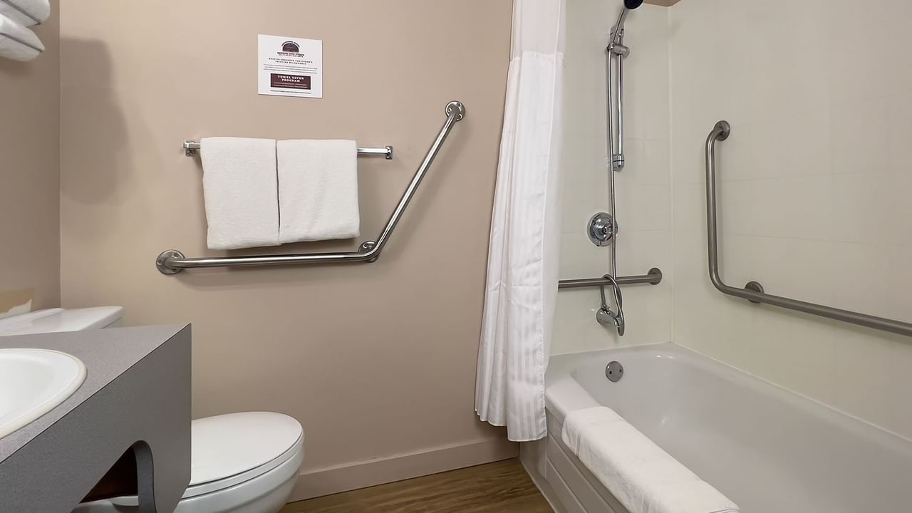 Accessible bathroom with sink, bathtub, grab bar, toilet, and towels