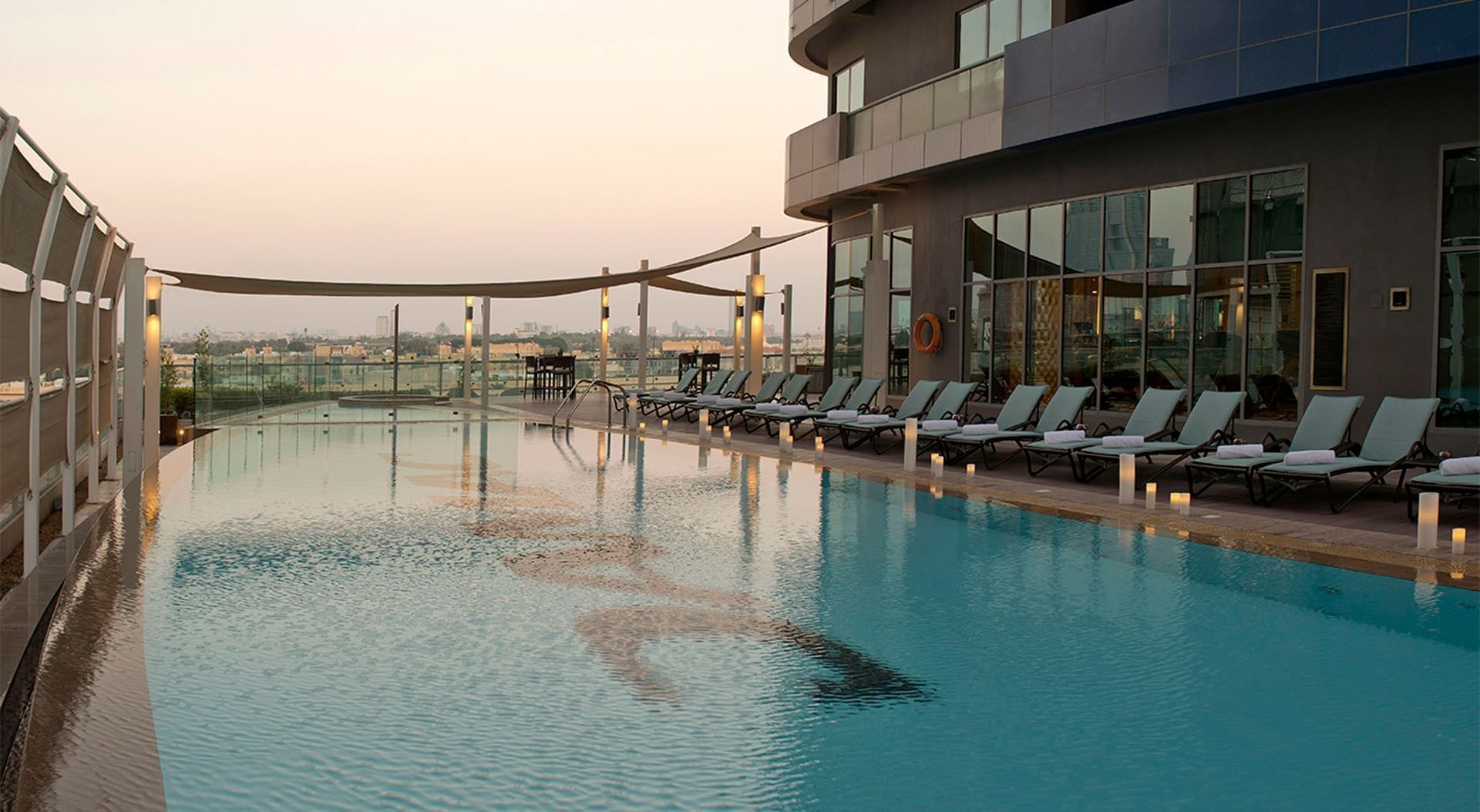Outdoor pool with loungers and city view at DAMAC Maison Mall street