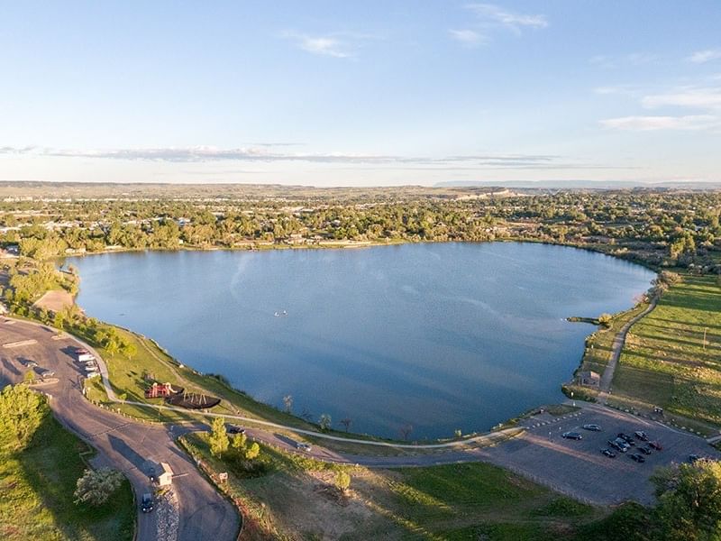 Aerial view of a serene blue lake surrounded by green spaces and parking areas at Lake Elmo State Park