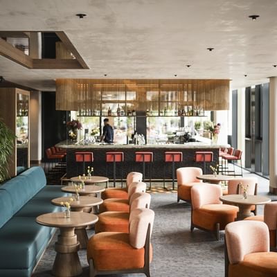 Interni di un bar con tavolo e divani, un bancone da bar e finestre in vetro.