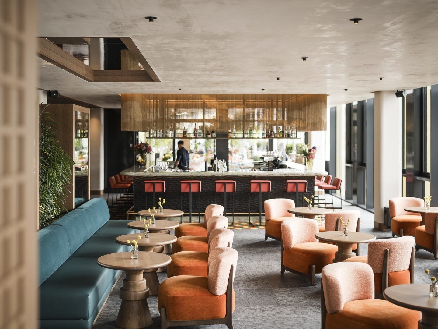 Interior of a stylish lounge with tables, chairs, a blue sofa, and a bar counter.