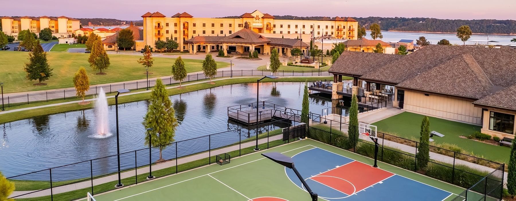 Exterior view of Shangri-La Resort and Golf Club with a basketball court, fountain pond, and hotel wing