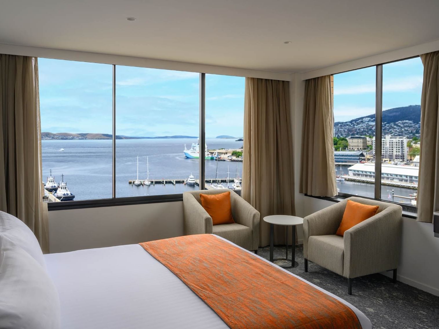 Executive room featuring a comfy bed and armchairs with a bay backdrop at Hotel Grand Chancellor Hobart