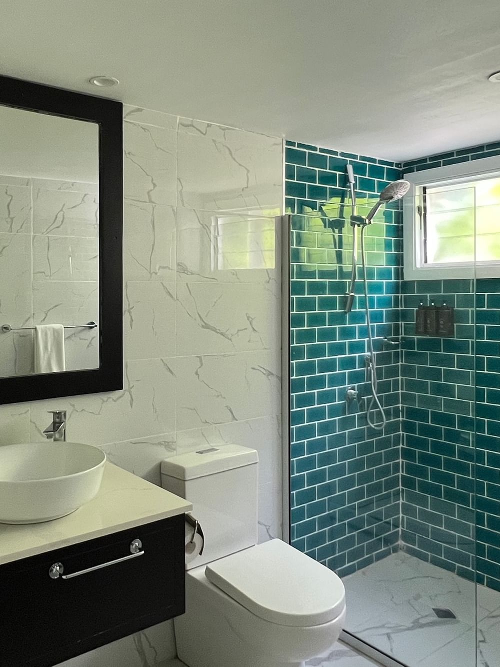 Modern bathroom with green tiled shower and white sink at Tambua Sands Beach Resort in Sigatoka.