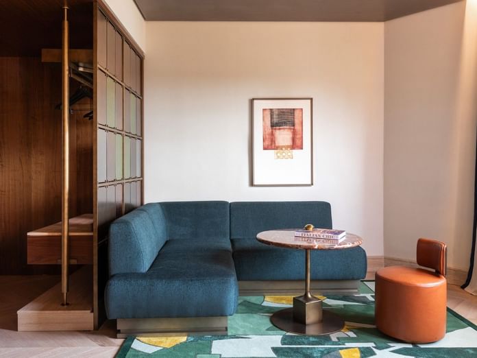 Modern 1 King Bed Suite living area with teal sofa, geometric rug, and framed artwork at The Thompson Rome, Roma.