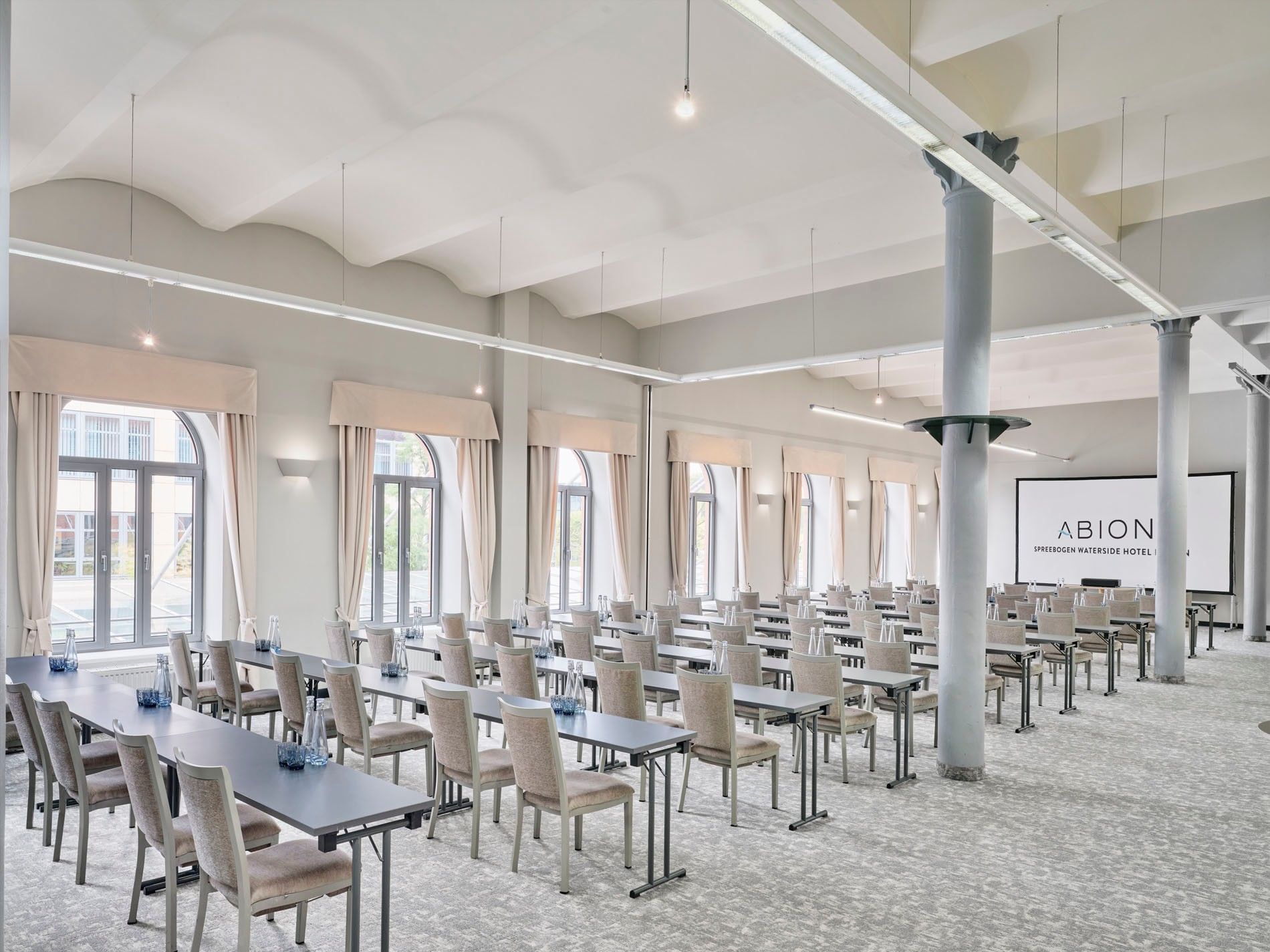 Meeting room with tables and chairs arranged in rows at Abion Spreebogen Waterside Hotel.