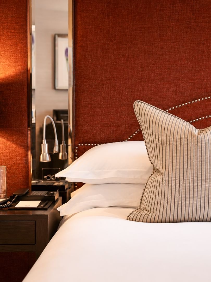 Deluxe King Bedroom detail with white bed, striped cushion, and bedside lamp at The Capital Hotel & Townhouse