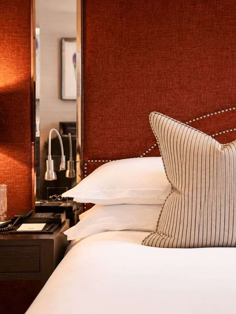 Deluxe King room at The Capital Hotel, Apartments & Townhouse - London, with large bed, nightstand, and red headboard.
