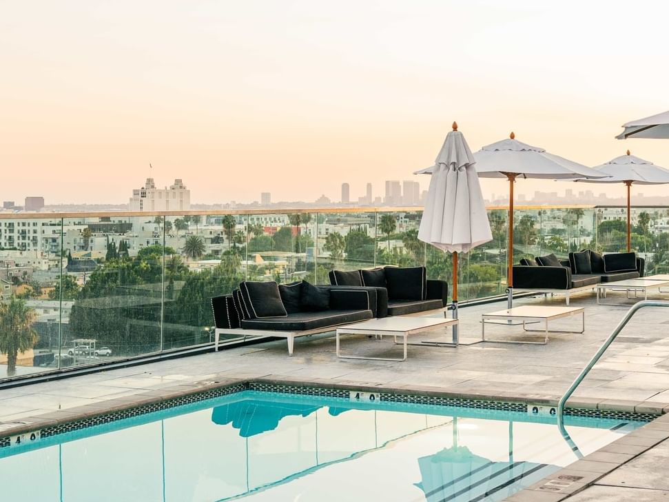 Bright blue sky over a rooftop pool with white lounge chairs and a view of Hollywood at The Godfrey Hotel Hollywood