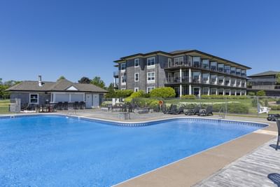 Lounge chairs by a wide outdoor pool under a sky at Rodd Brudenell River Resort, one of the premier places to stay in PEI
