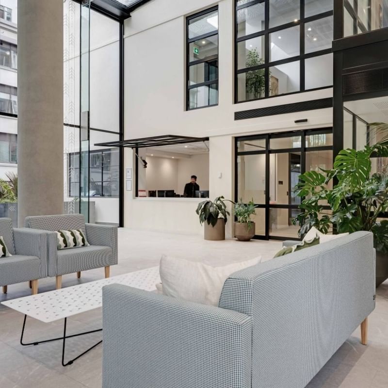 Modern lobby with gray seating, potted plants, and floor-to-ceiling windows at UniLodge Auckland Central