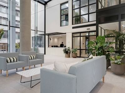 Modern lobby with gray seating, potted plants, and floor-to-ceiling windows at UniLodge Auckland Central