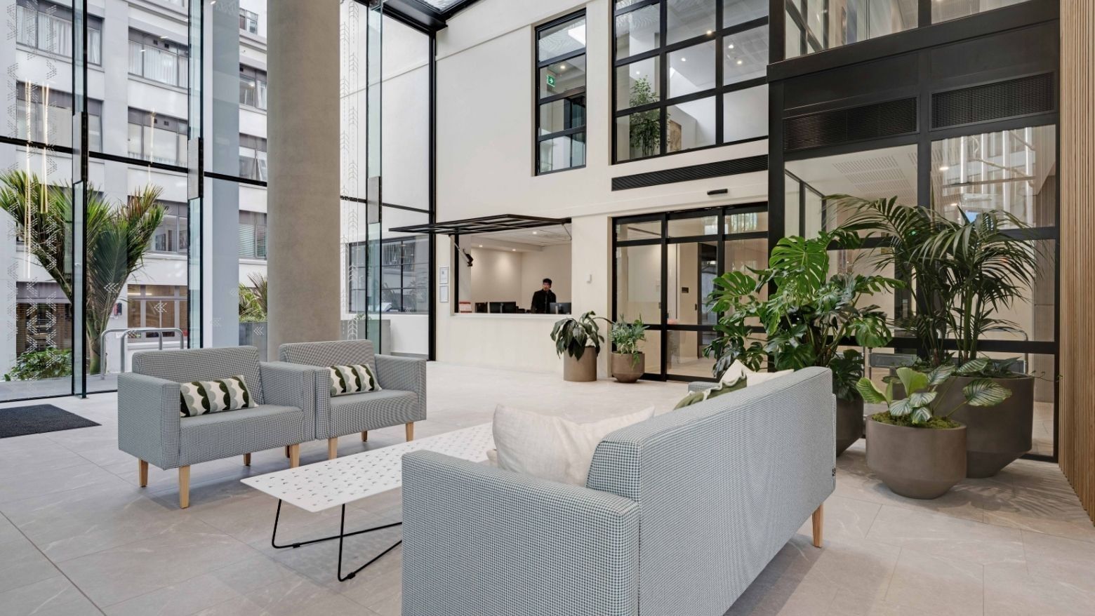 Modern lobby with gray seating, potted plants, and floor-to-ceiling windows at UniLodge Auckland Central