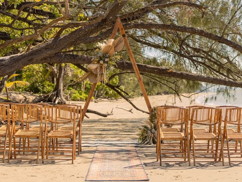 Outdoor wedding setup on the beach with chairs and wooden arch in Four Mile Beach at Pullman Port Douglas
