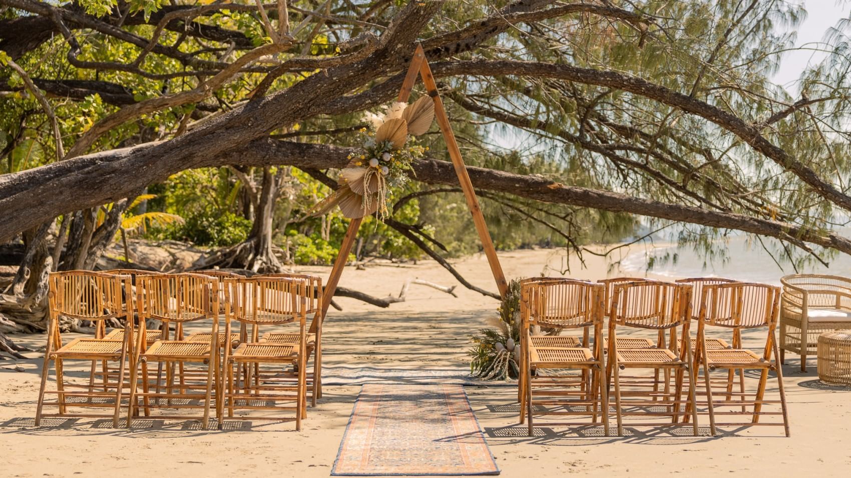 Outdoor wedding setup on the beach with chairs and wooden arch in Four Mile Beach at Pullman Port Douglas