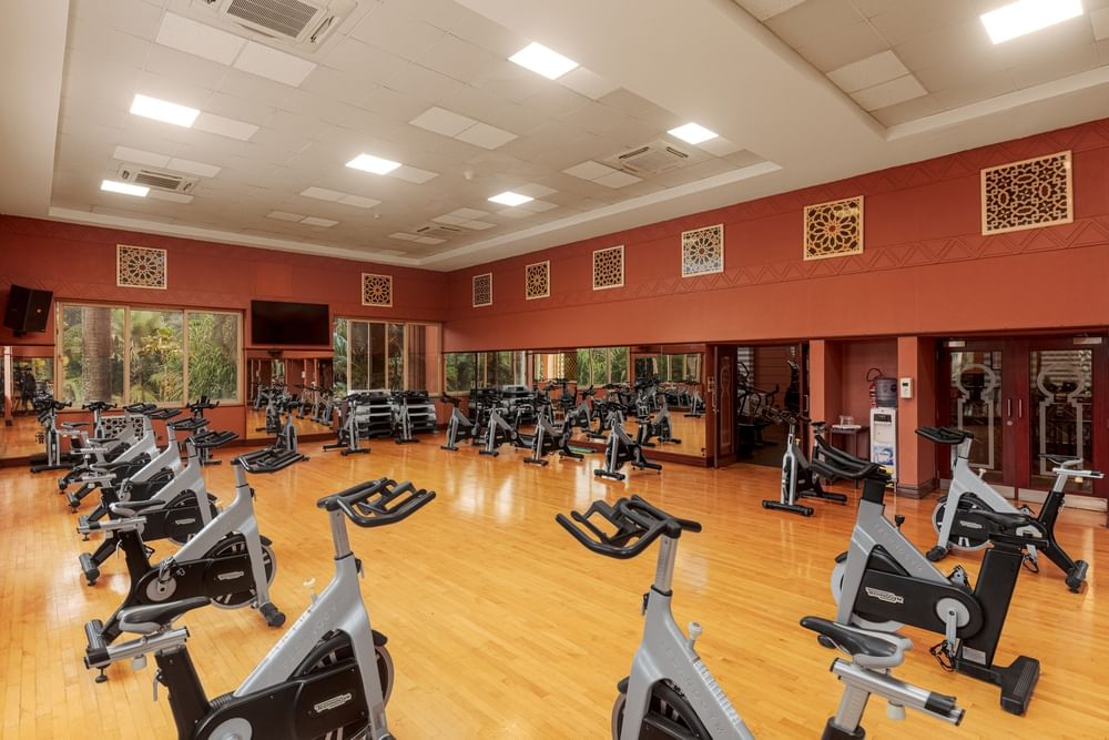 Spacious fitness center with stationary bikes and exercise equipment on polished wood floors at Kampala Serena Hotel