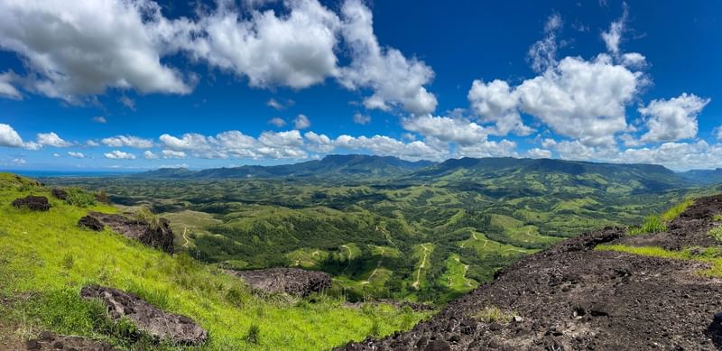 Panoramic view of lush green hills and distant mountains under a cloudy blue sky at TokaToka Resort Nadi Fiji نادي