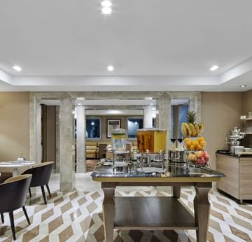 Modern buffet area with fruit and beverages displayed in Breakfast Restaurant at Titanic Comfort Mitte