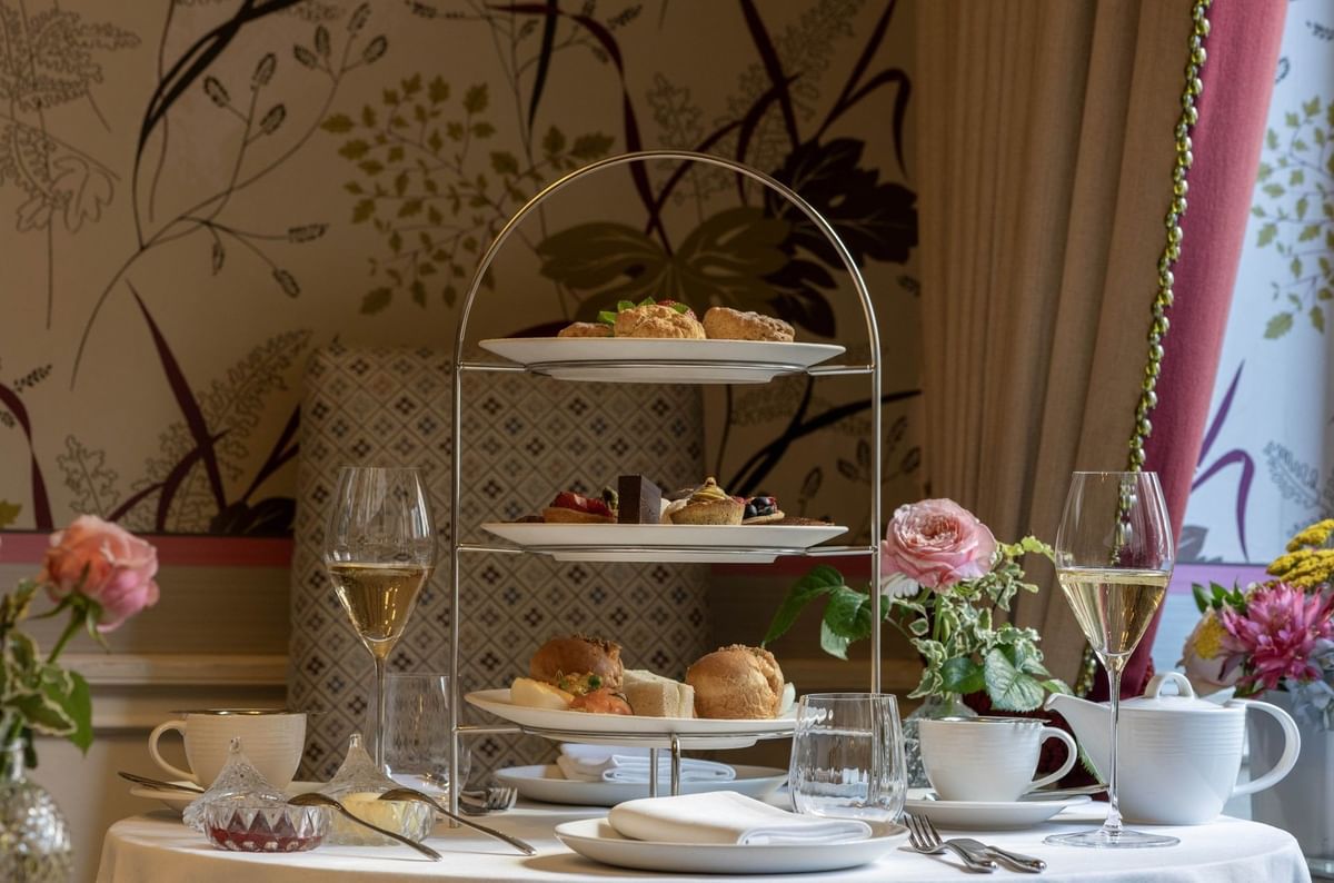 Afternoon tea set on a table by floral wallpaper under soft lighting at The Capital Hotel, Apartments and Townhouse