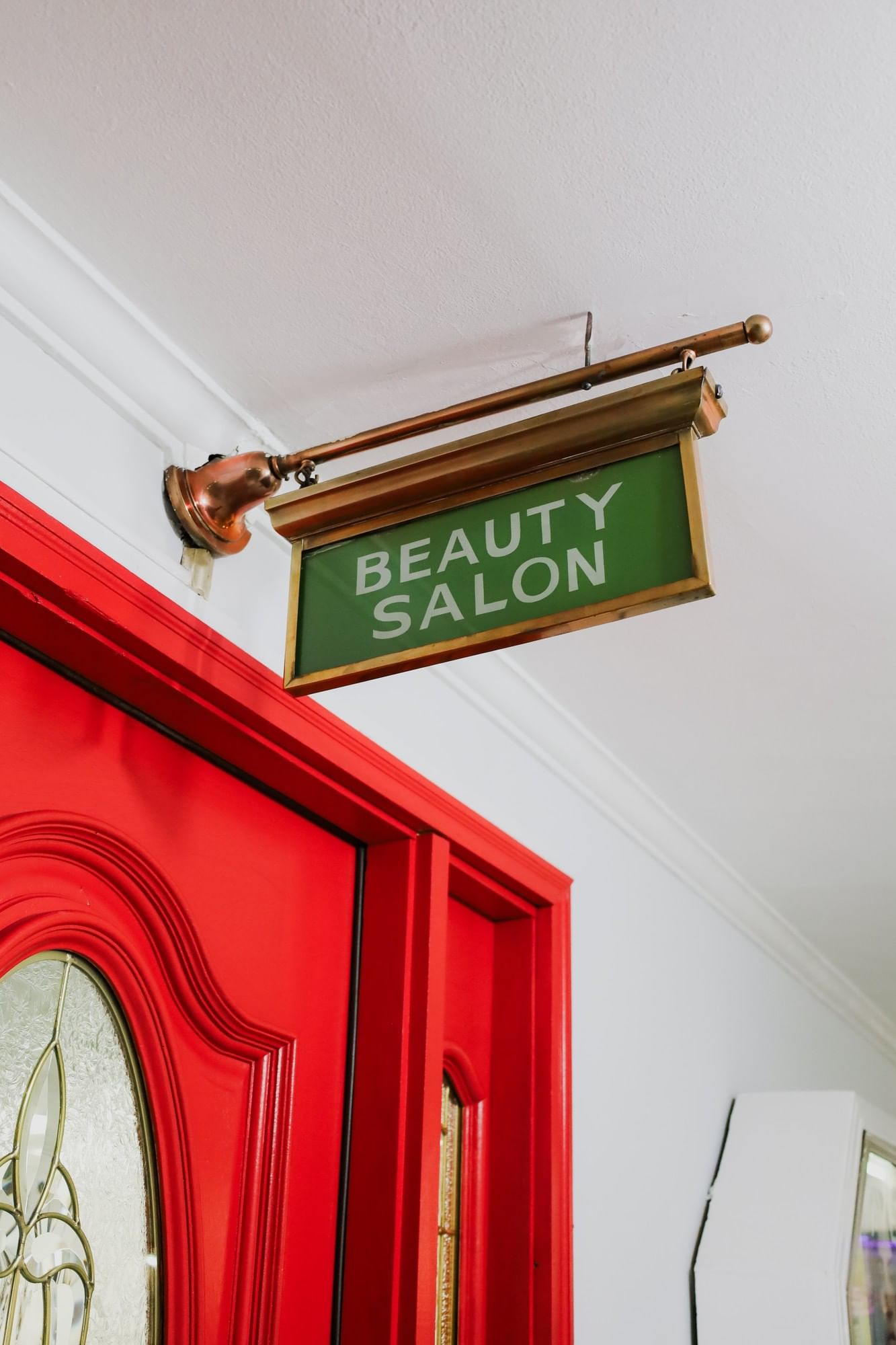 Green Beauty Salon sign in a gold frame by a red door under a white ceiling at Arlington Resort Hotel & Spa