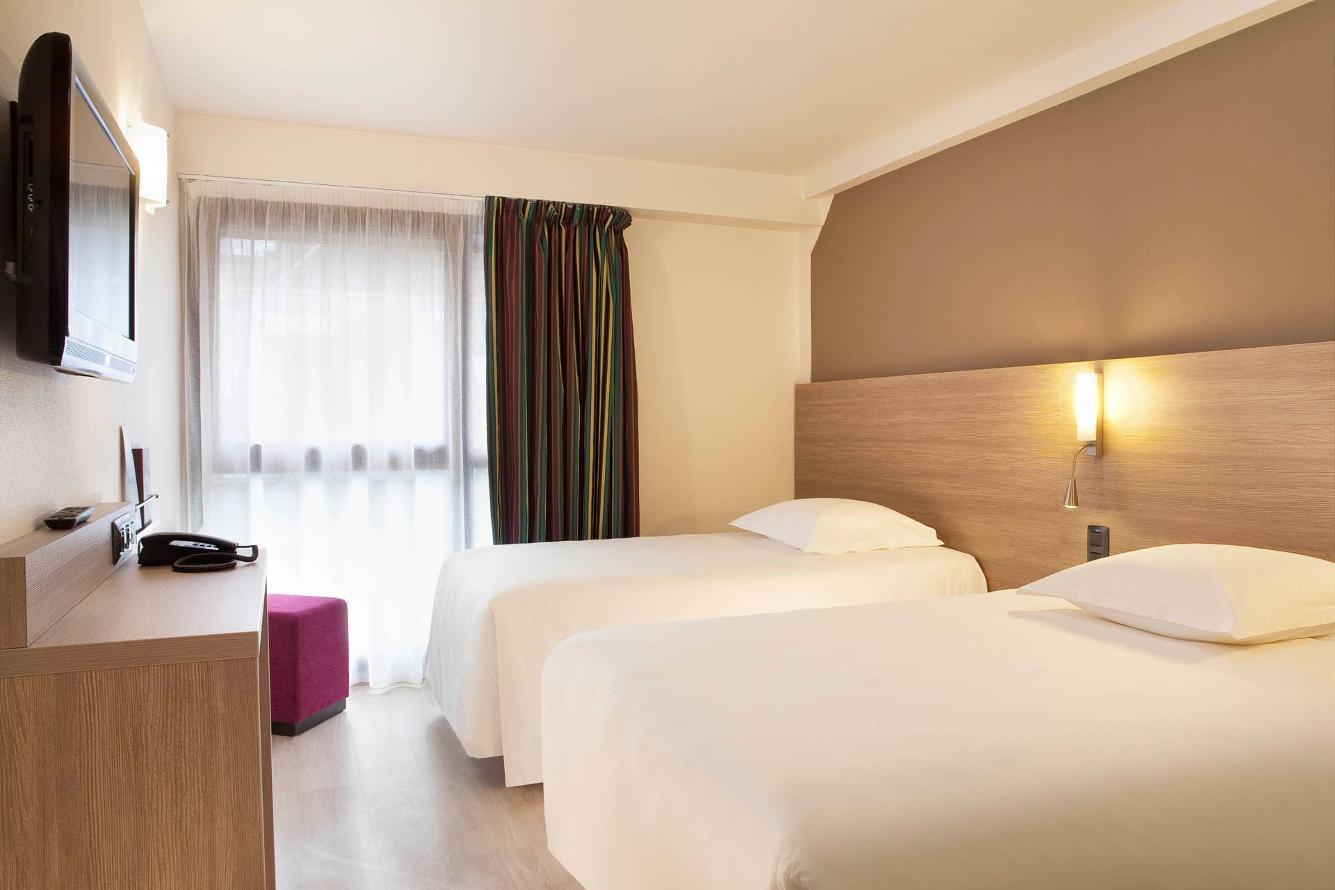 Deux lits et télévision dans une chambre à Escale Oceania Quimper