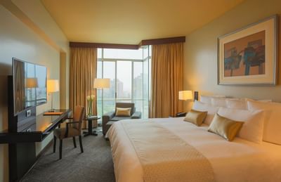 TV, work desk, and lounge chair by the bed in Junior Suite at Hotel Los Delfines & Casino