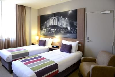 Superior room with 2 Single Beds and a chair at Grosvenor Hotel