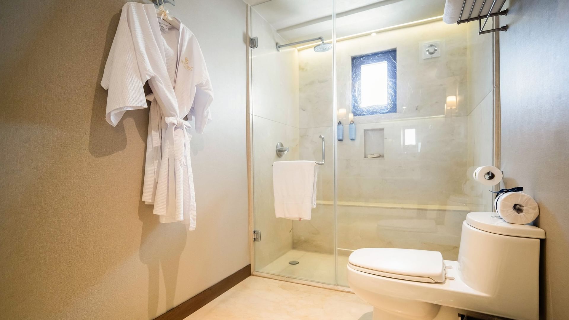 Bathroom with shower, toilet, and bathrobe at Quinta Real Puebla in Heroica Puebla de Zaragoza.