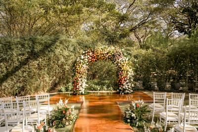 Outdoor wedding setup with floral arch and white chairs at El Mangroove Hotel