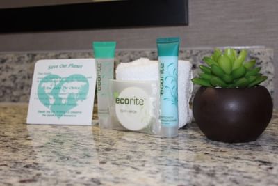 Bathroom counter at Moab Valley Inn with eco-friendly toiletries, a folded towel, and a sustainability message card