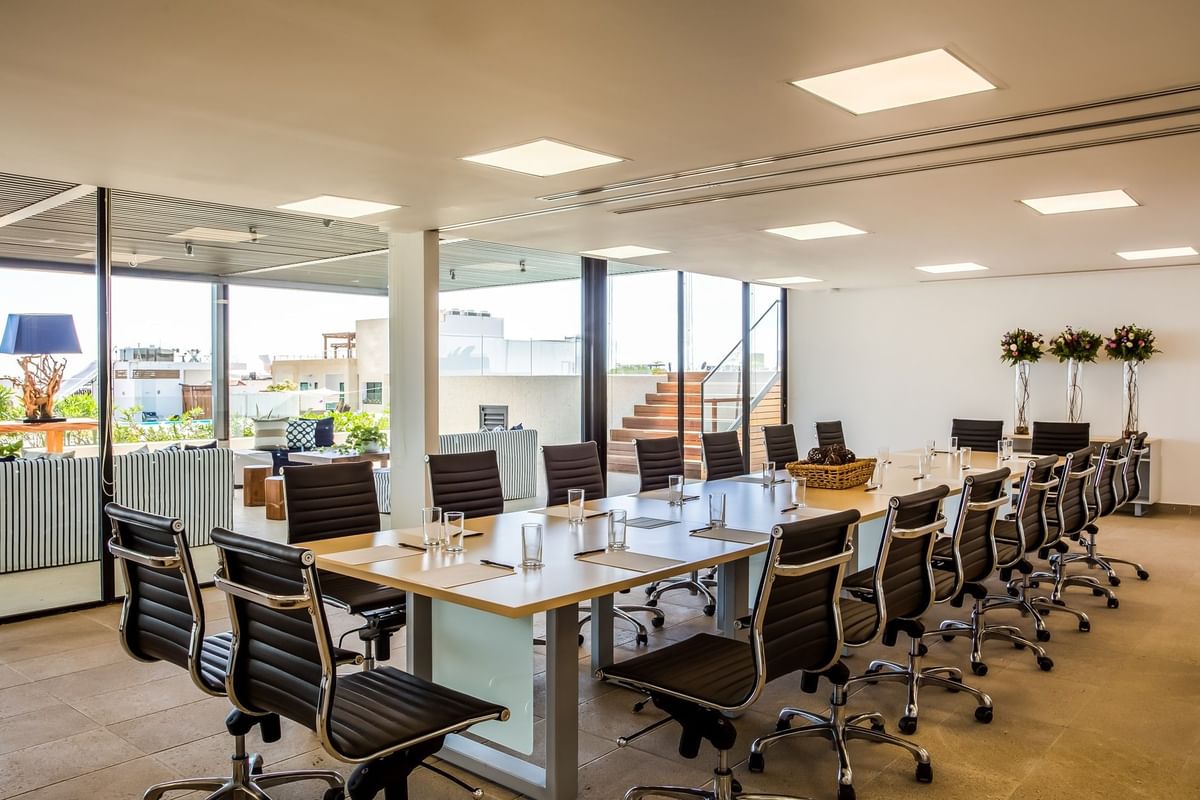 Sala de conferencias soleada con mesa larga y sillas ejecutivas cerca de terraza al aire libre en Fiesta Inn