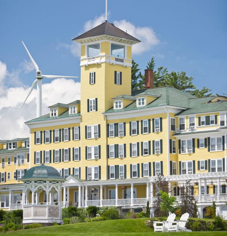 Close-up of Mountain View Grand Resort & Spa\'s yellow tower with an American flag, beside a gazebo under blue sky