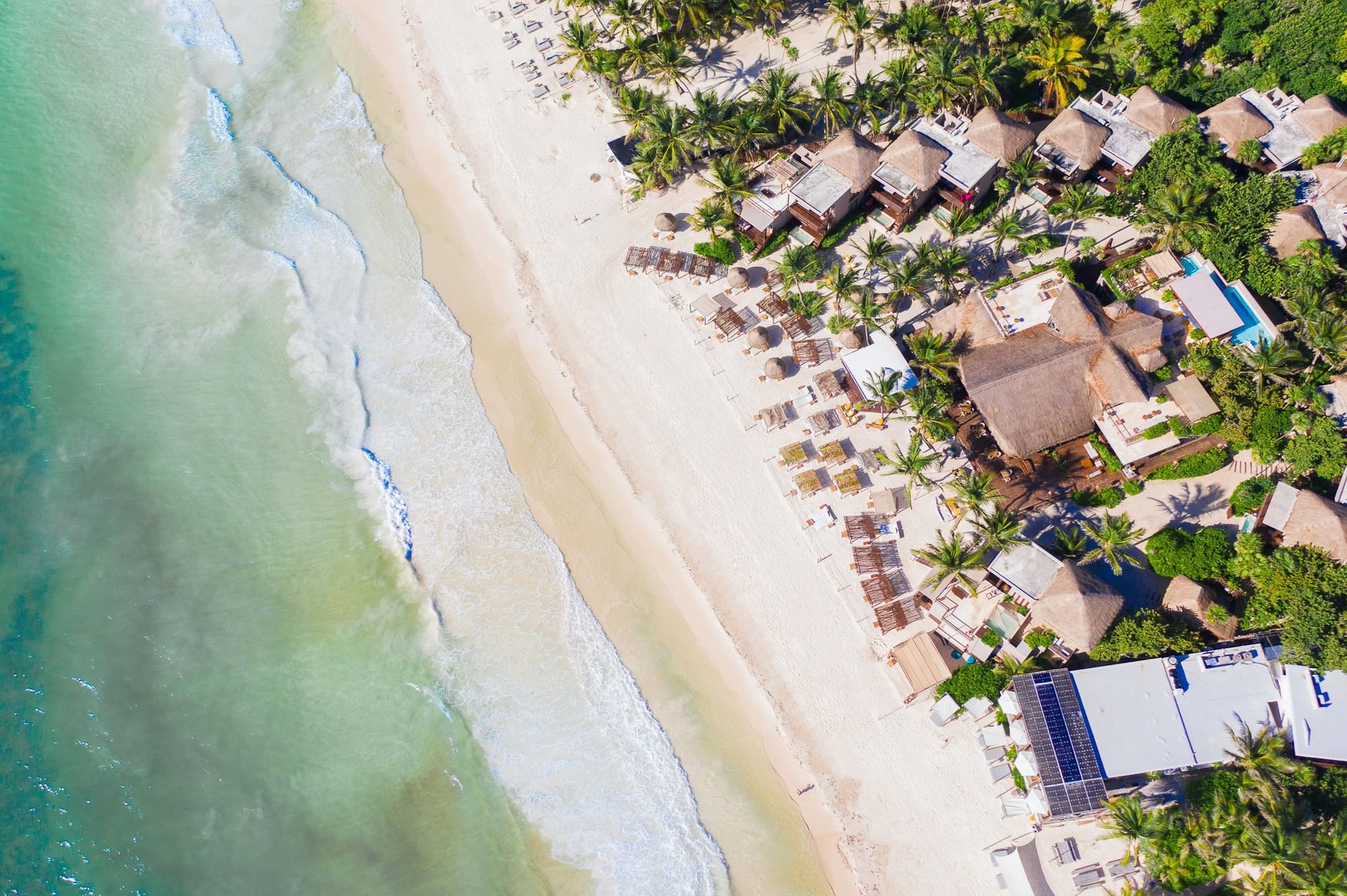 Aerial view of La Zebra Tulum on white sand beside turquoise Caribbean water.