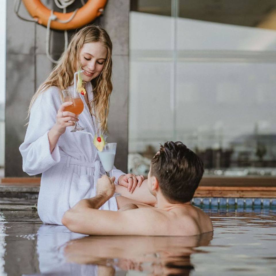 Couple posing with cocktails by the pool at LK Cikarang Hotel & Residences