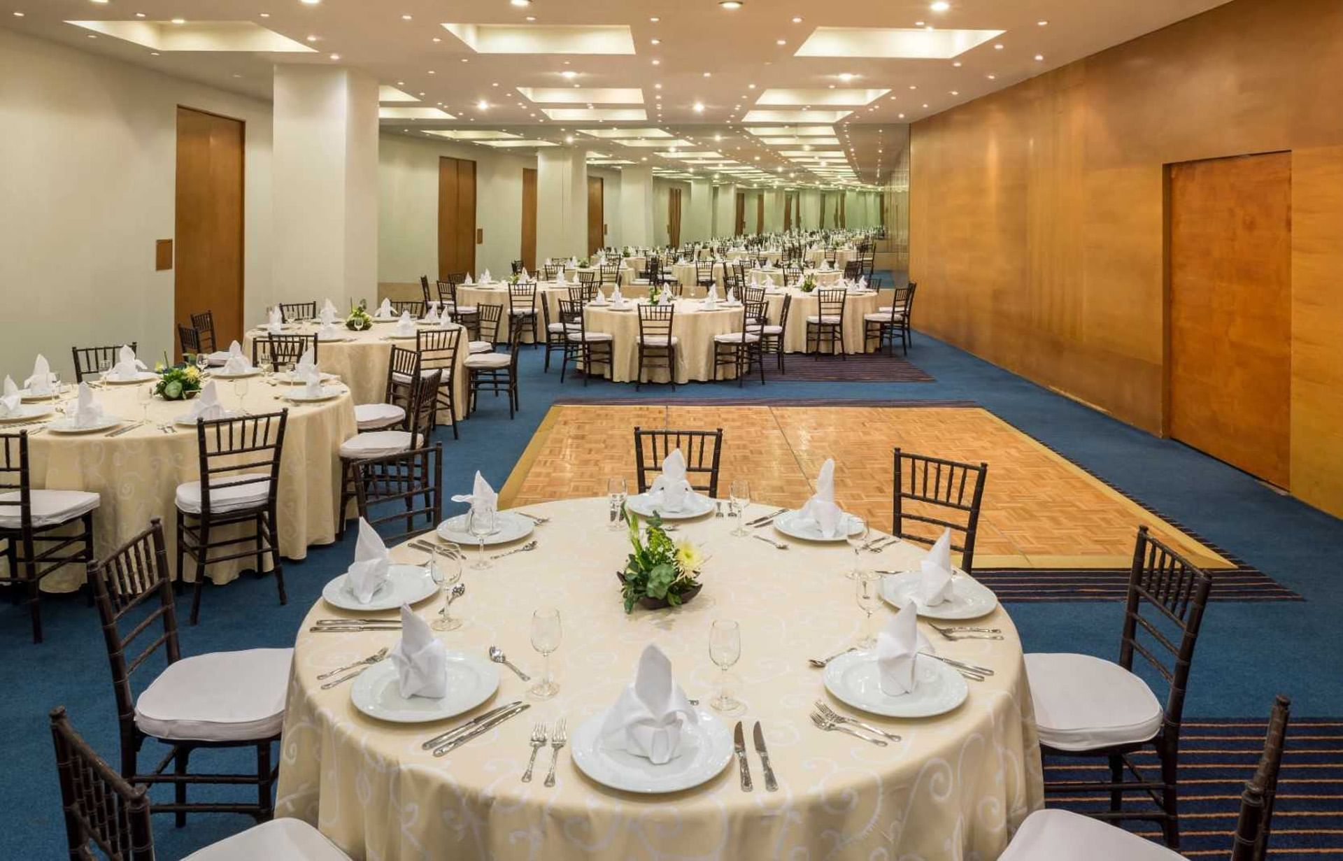 Salón elegante con mesas redondas, manteles crema y pista de baile en Real Inn San Luis Potosí