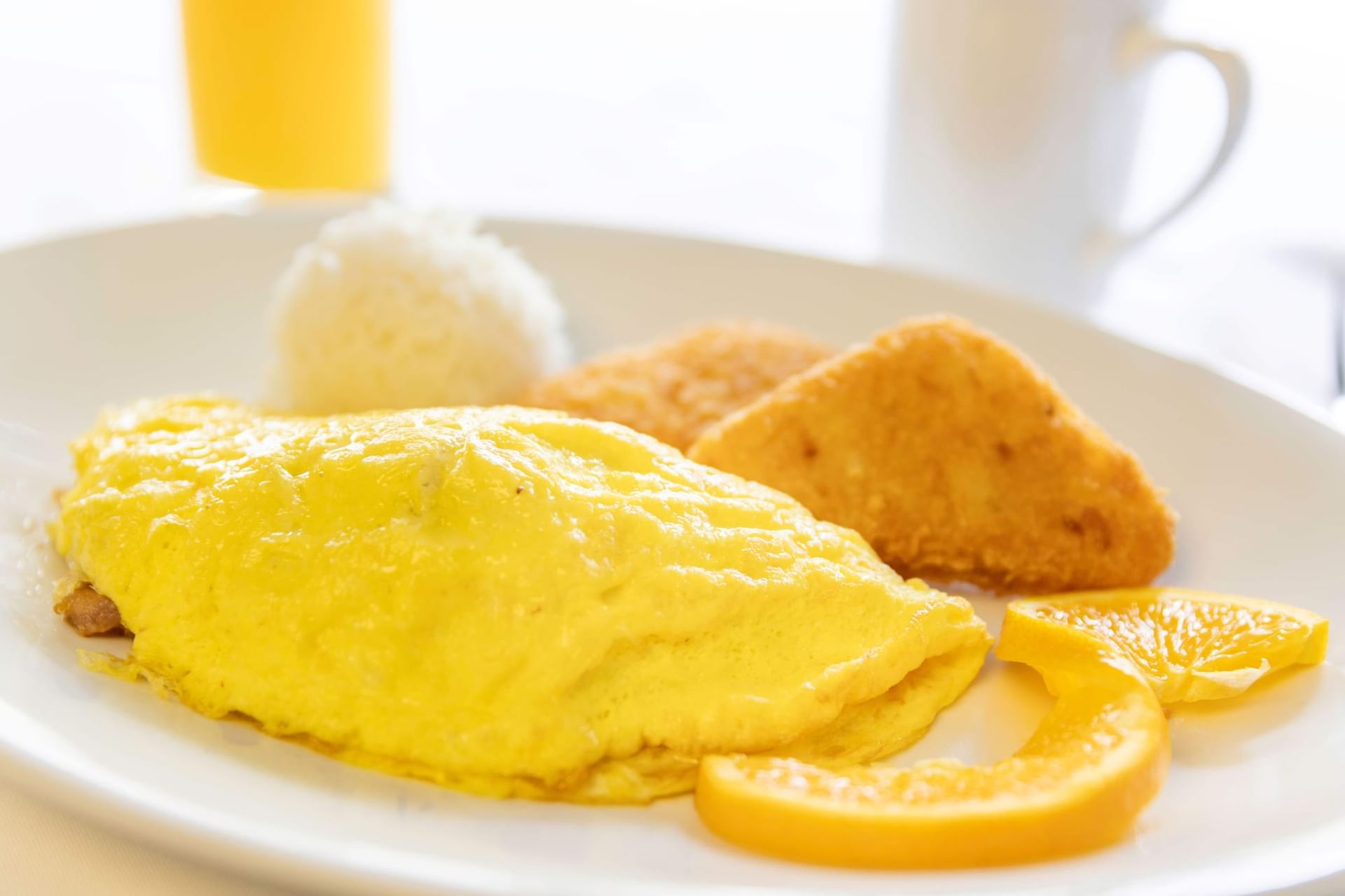 a plate of food with an omelette, rice, toast, and orange slices