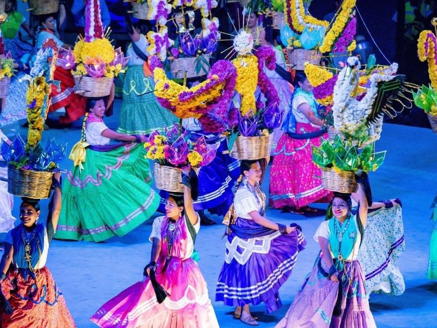 Bailarines tradicionales vibrantes con faldas coloridas y tocados florales cerca de Camino Real Hotels