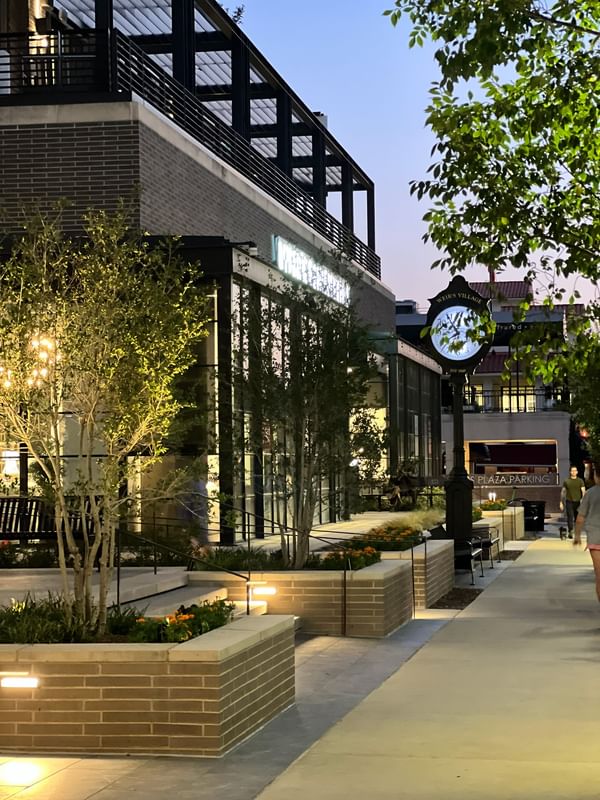 Outdoor walkway by brick planters under a vintage clock tower at Warwick Melrose Dallas