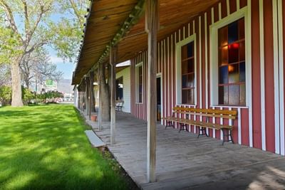 Rustic red and white striped building with wooden benches at Buffalo Bill Village surrounded by greenery