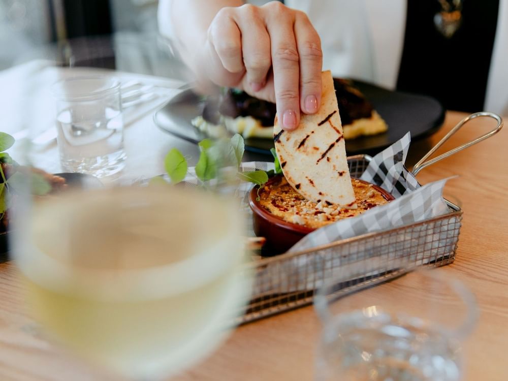 Hand dipping a chip into a dip at an event promoting The Green Neighbour Nights.