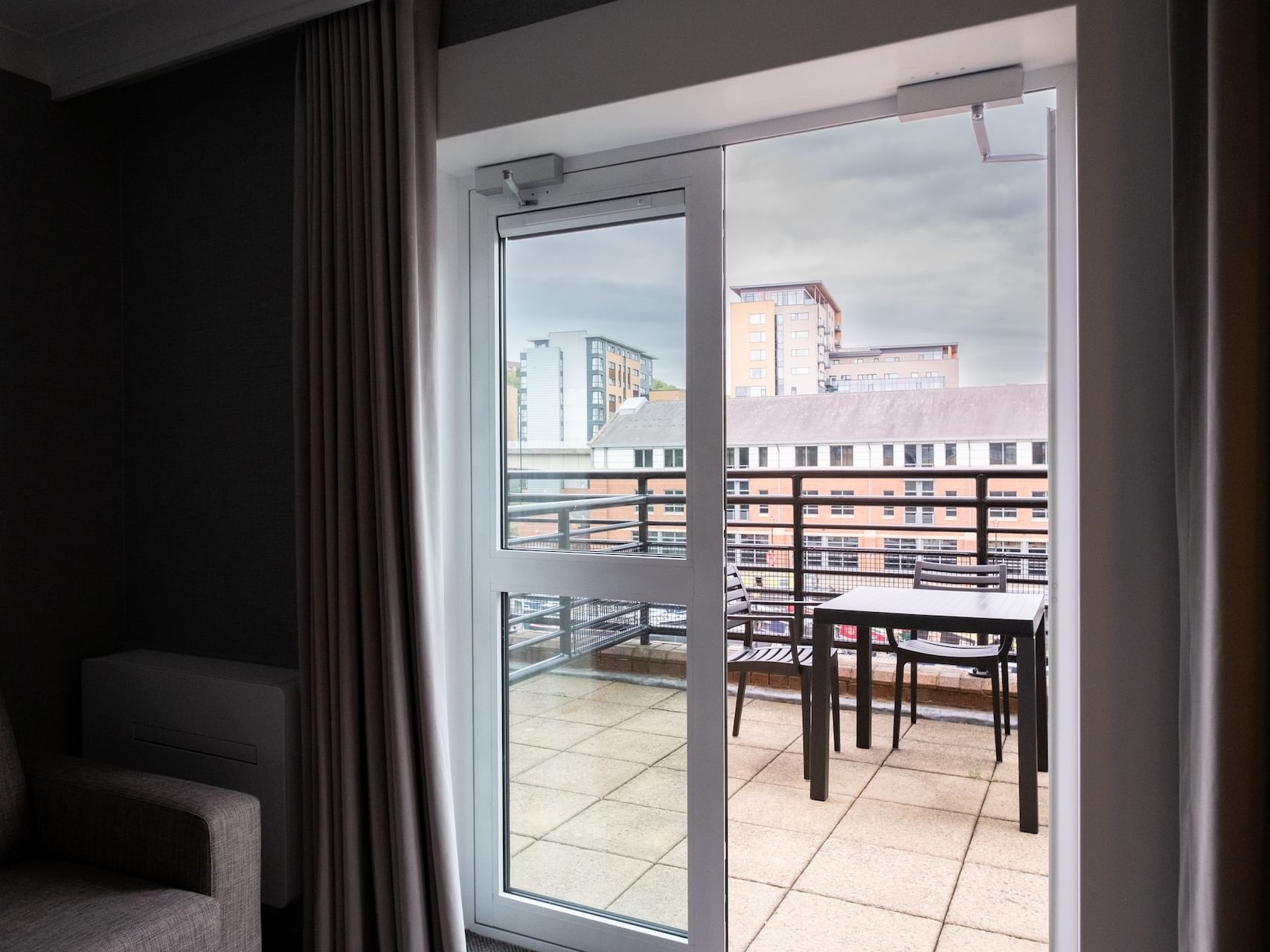View of a cityscape through a glass door leading to a balcony of Deluxe Suite at Sandman Signature Sheffield Quays Hotel