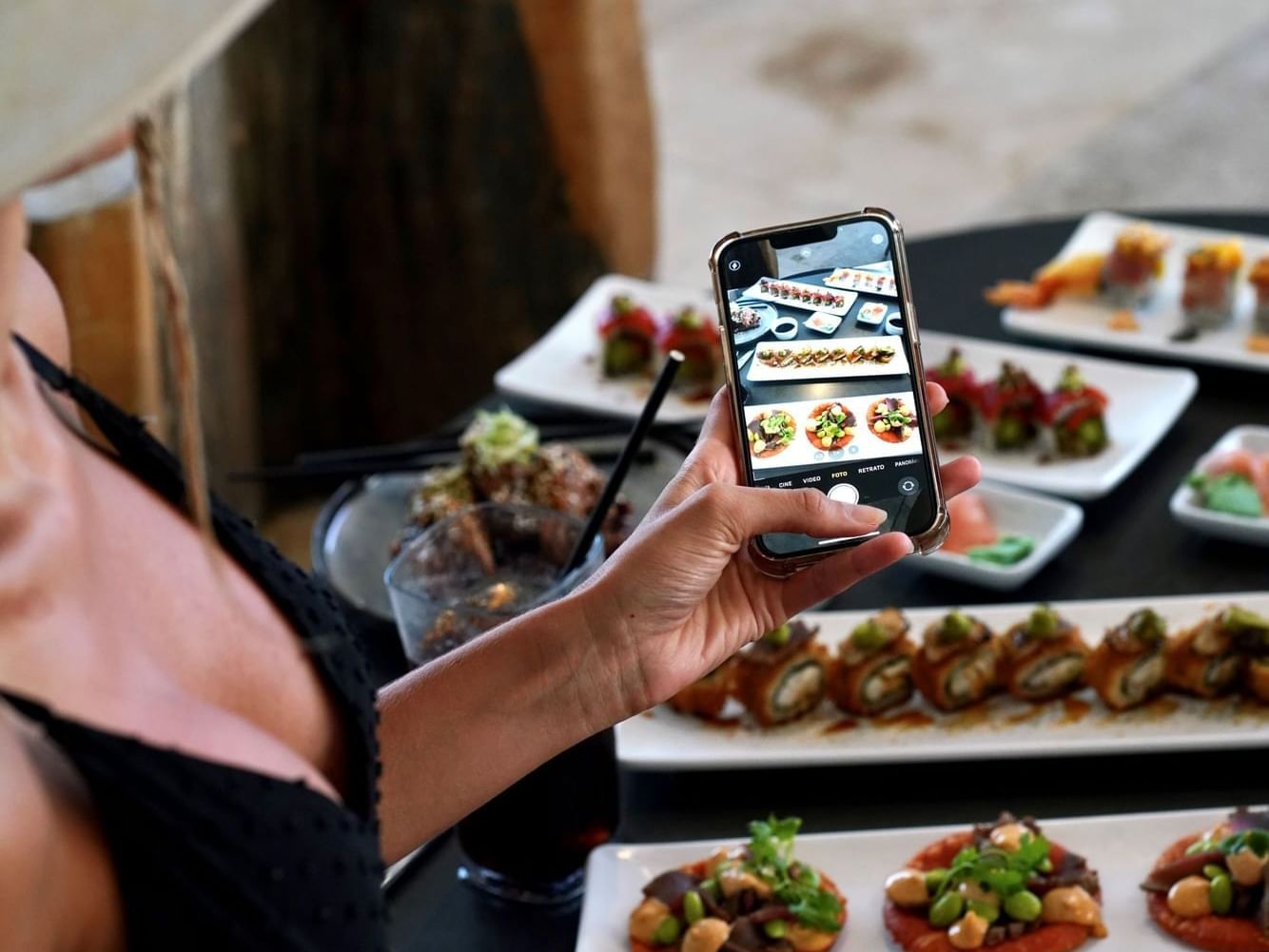 A woman capturing a photo of a delicious meal on a plate at Alaia Belize Autograph Collection