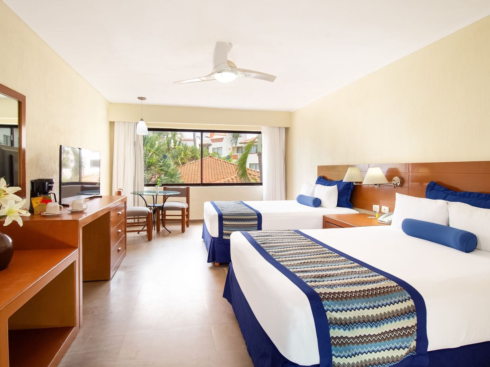 TV and dressing table facing the beds in Standard Double Room at Plaza Pelicanos Grand Beach Resort