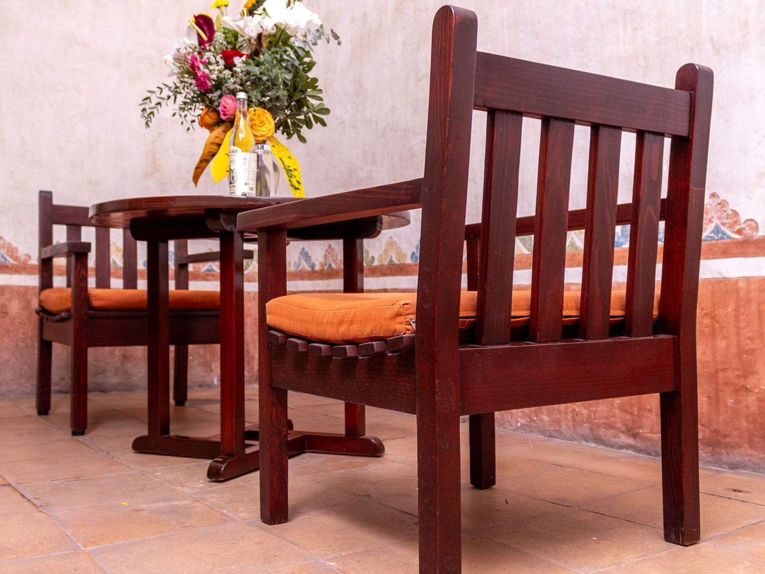 Mesa y sillas de madera con flores en Suite Gobernador King en Quinta Real Oaxaca