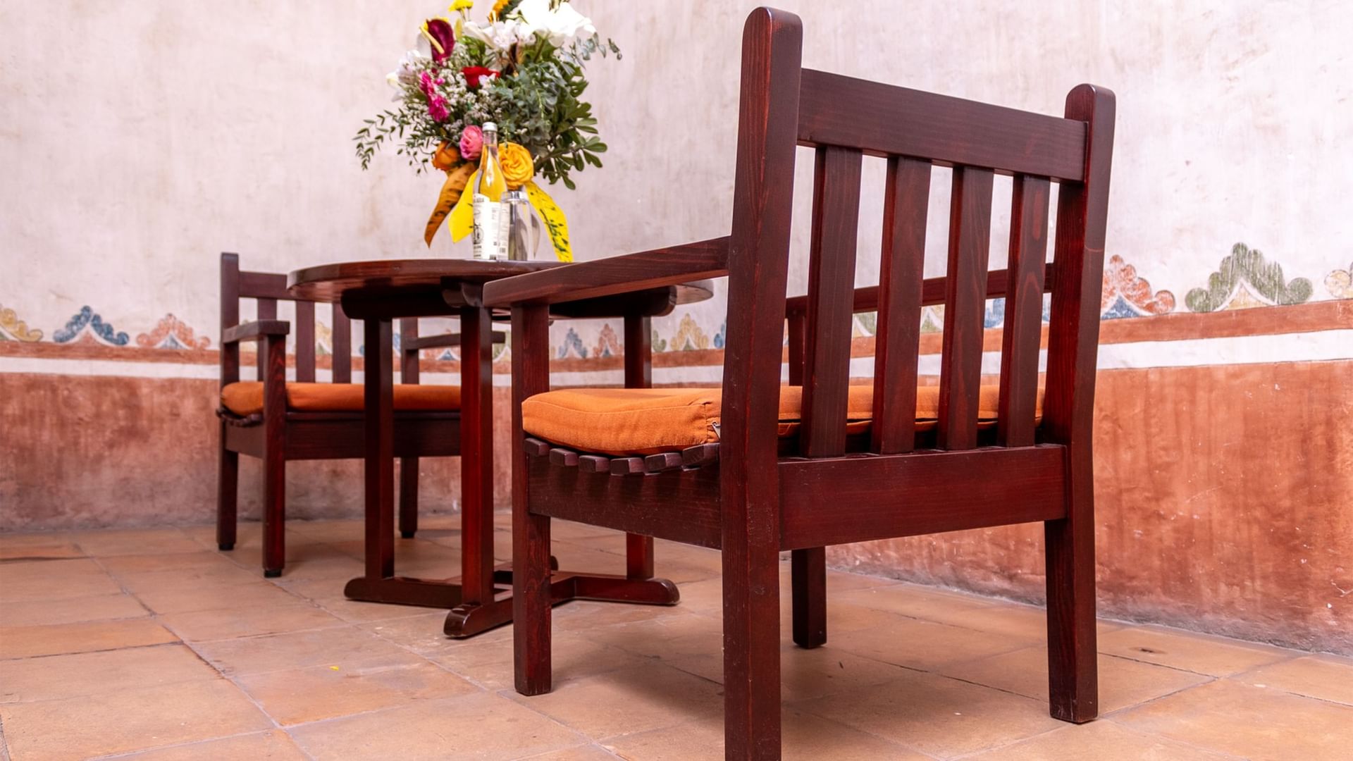 Mesa y sillas de madera con flores en Suite Gobernador King en Quinta Real Oaxaca