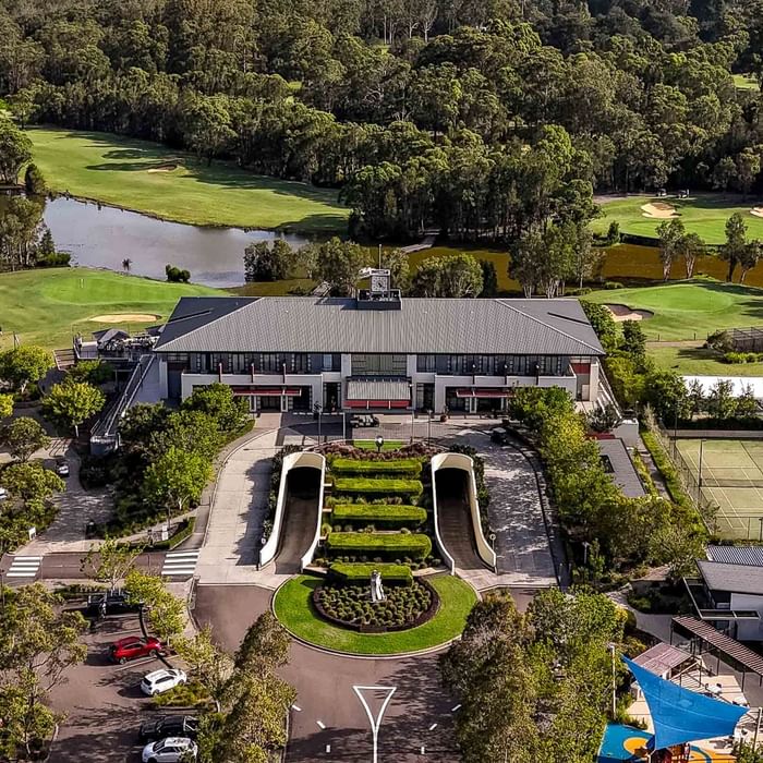 Aerial view of a resort with buildings, tennis courts, landscaped gardens, and a golf course.